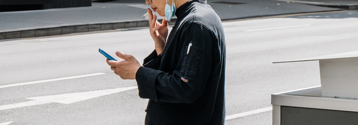 man smoking a cigarette with mask on his chin